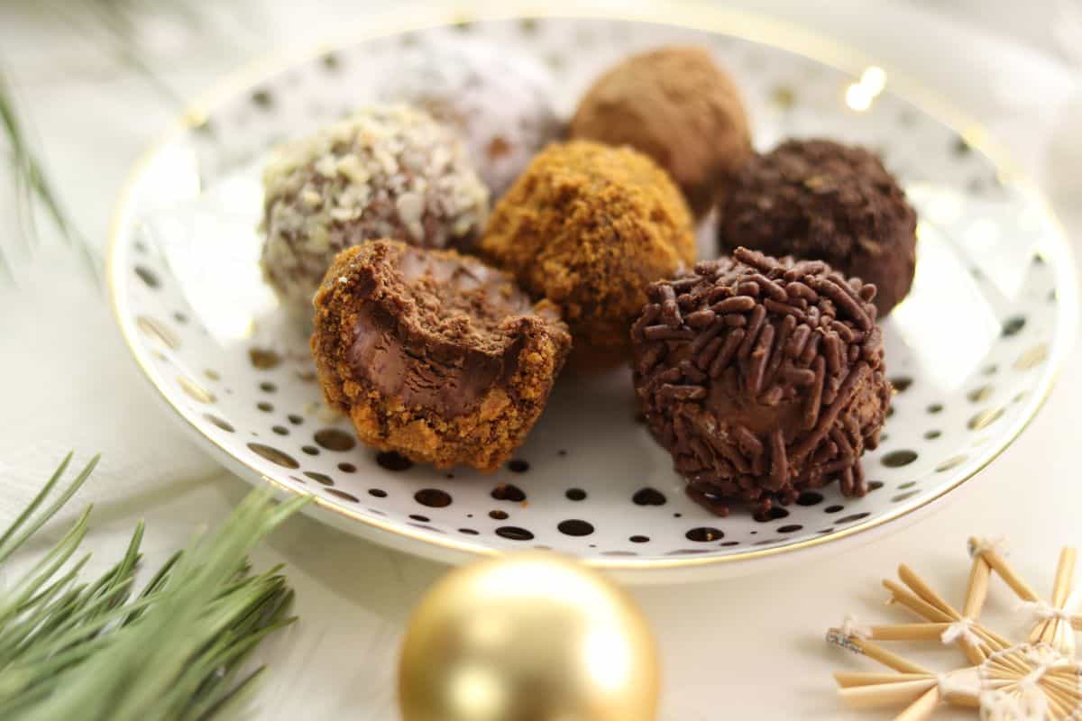 Assorted Rumkugeln aka German rum balls on a white and gold Christmas plate.