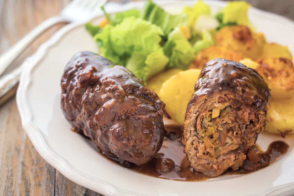 German beef rouladen arraged on a plate in a festive setting.