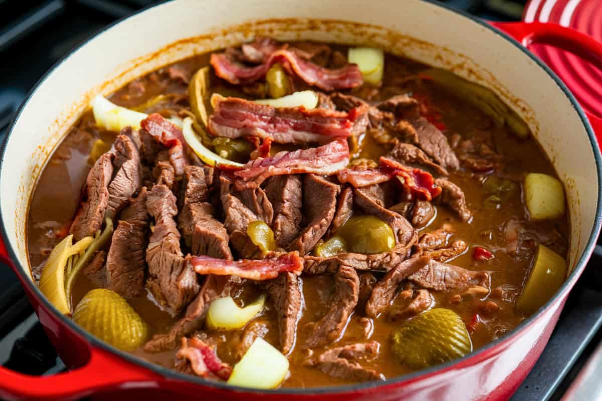 Rouladeneintopf aka German rouladen stew in a large red cast iron pot.