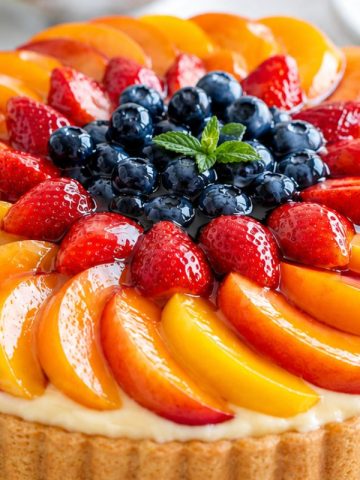 Colorful German Obsttorte fruit tart with strawberries, blueberries, and peaches for dessert.